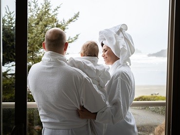 A family of three, in bathrobes, enjoys the view from the balcony.