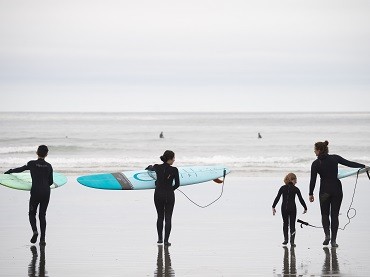 A family of four surfs the waves at Cox Bay